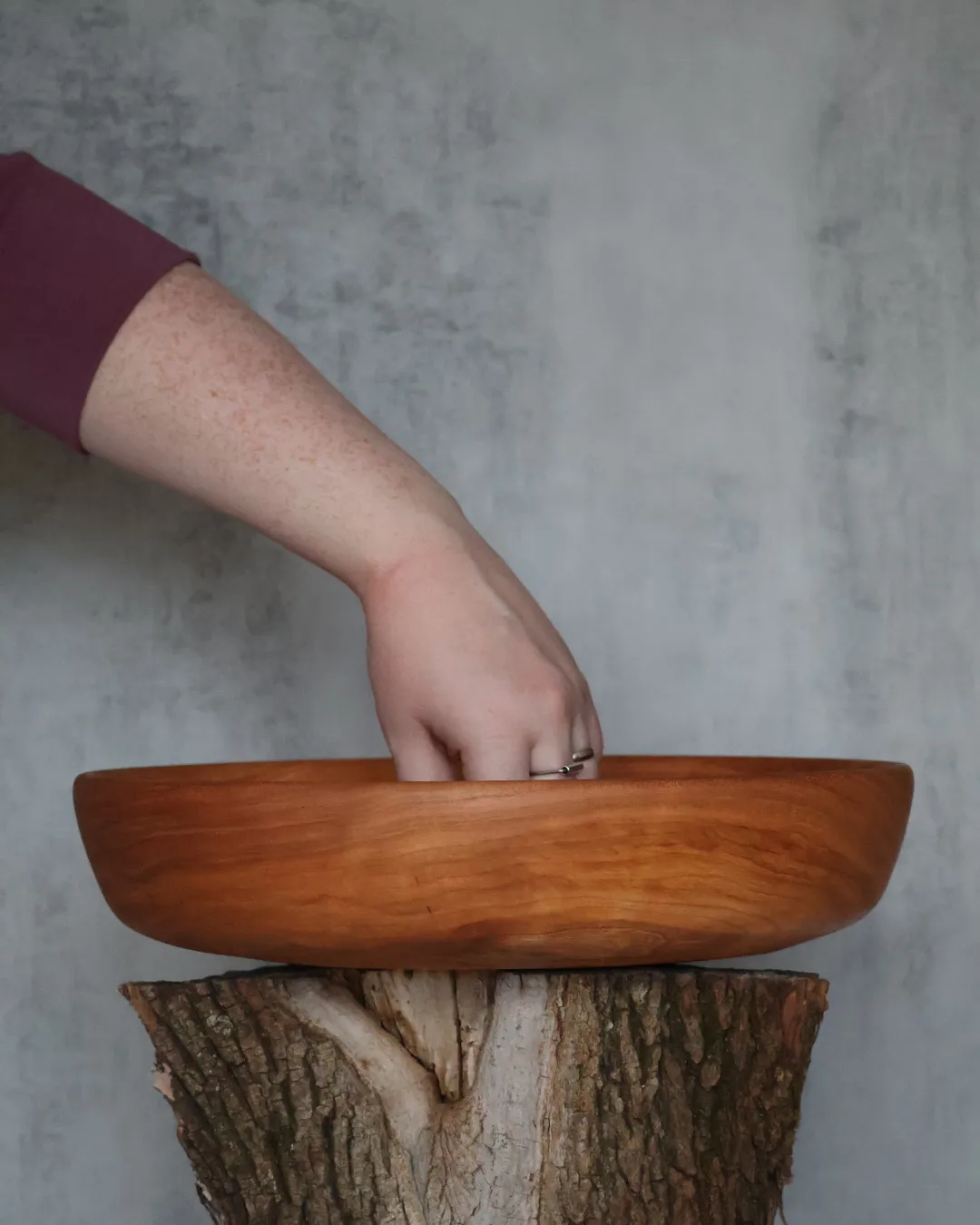 Hand-turned cherry wood platter displayed on rustic log stump