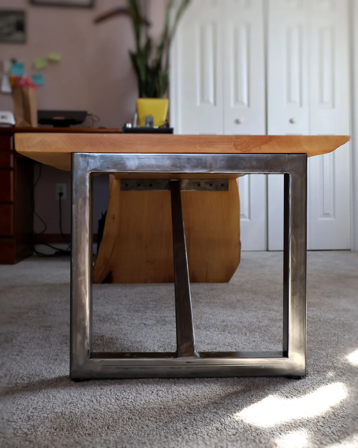 Underside view of live-edge maple waterfall table with steel and wood legs
