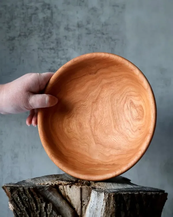 Hand-turned shallow cherry bowl held to show stunning interior grain pattern