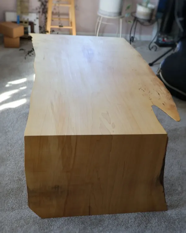 Live-edge maple waterfall table viewed from the end showing continuous grain