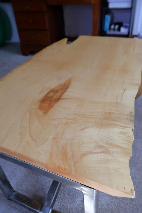 Close-up of live-edge maple table surface showing natural wood grain and spalting