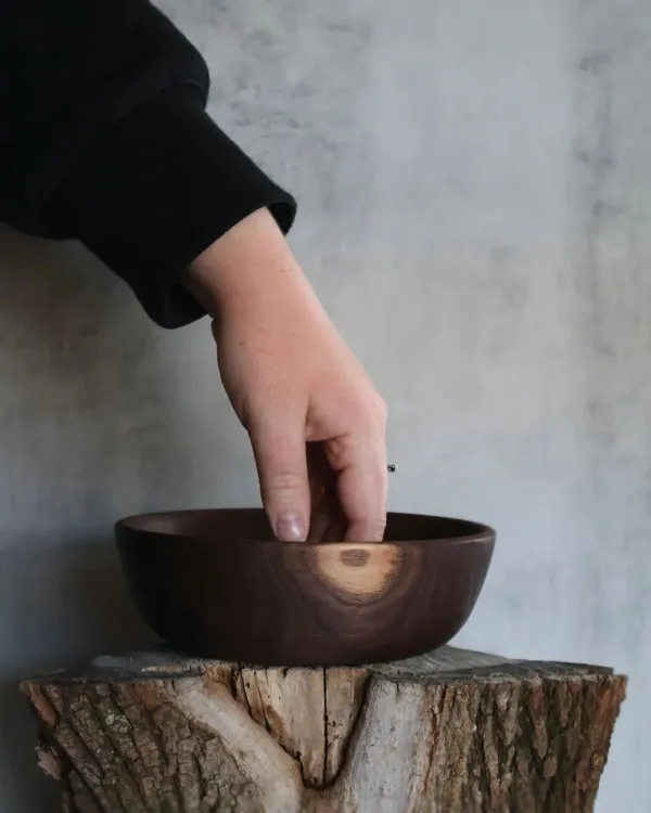 Hand-turned walnut bowl with natural sapwood accent displayed on log stump