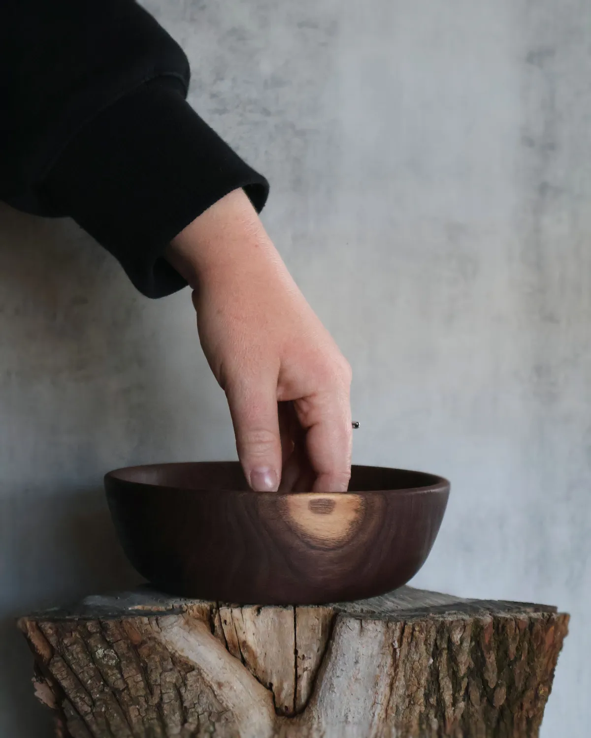 Hand-turned walnut bowl with natural sapwood accent displayed on log stump